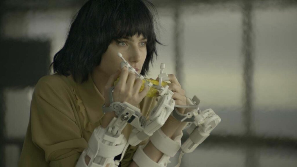 Une femme mange du maïs avec des mains robot-prothèse.